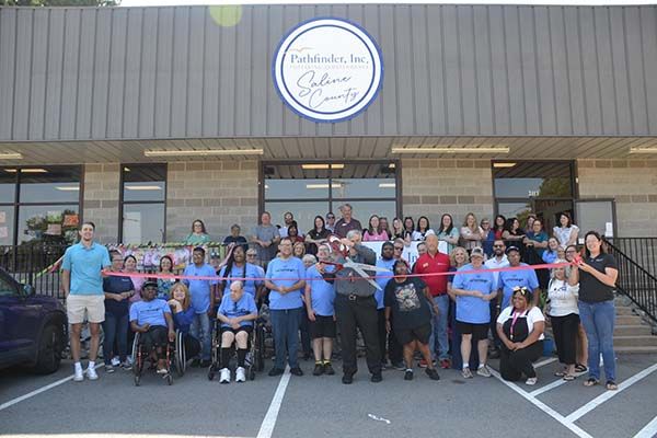 pathfinder inc saline county ribbon cutting ceremony, group of people standing in front of building with scissors opened about to cut ribbon